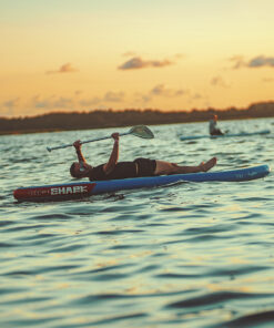 mees selili SUP laual, tagataustal päikeseloojang